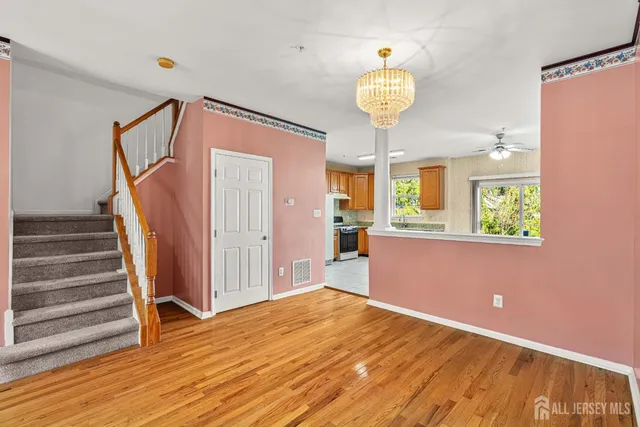 a view of empty room with wooden floor and fan