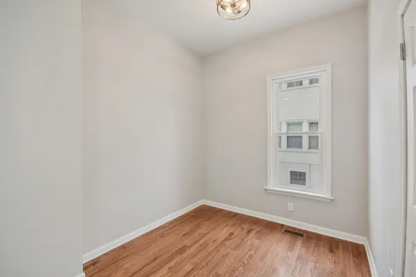 a view of an empty room with a window and wooden floor