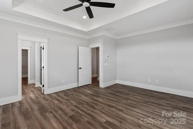 an empty room with wooden floor and ceiling fan