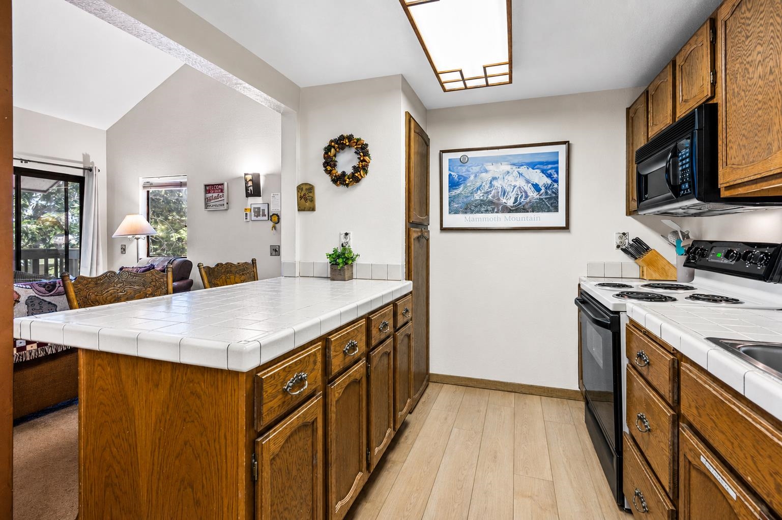153 Lake Mary Road, Unit 114 Mammoth Lakes, CA 93546 - Photo 6 of 22 Kitchen featuring wood-finish flooring, tile countertops, a built-in microwave, and a black range