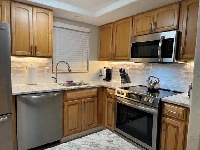 a kitchen with stainless steel appliances a stove microwave and sink