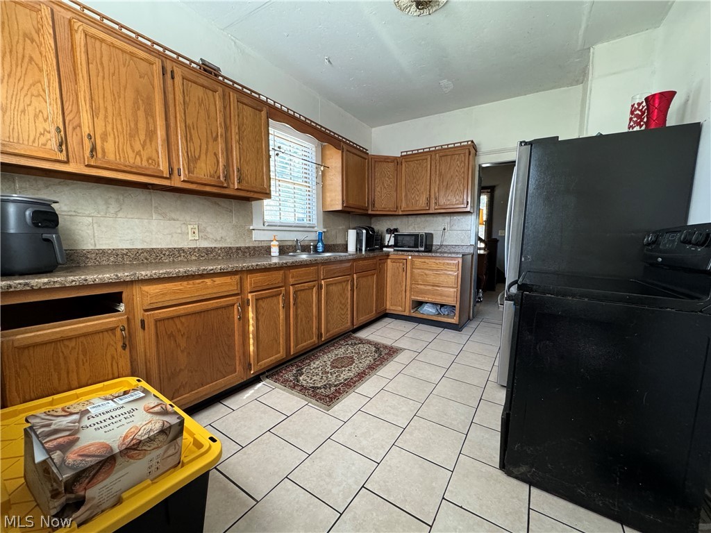 709 Fulton Road Northwest Canton, OH 44703 - Photo 6 of 20 Kitchen featuring wood cabinetry, laminate countertops, a tile backsplash, and tile flooring