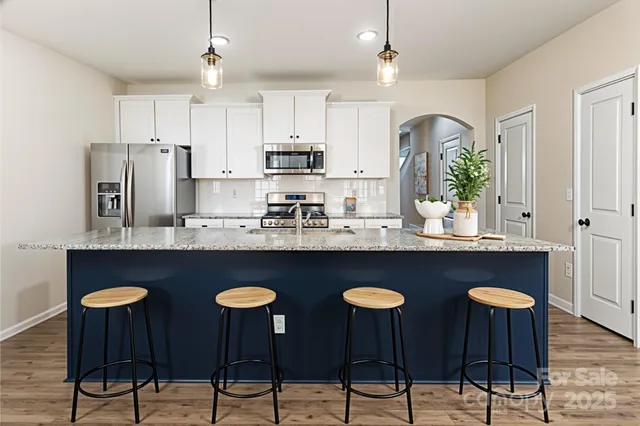 a kitchen with stainless steel appliances granite countertop a table chairs stove and refrigerator