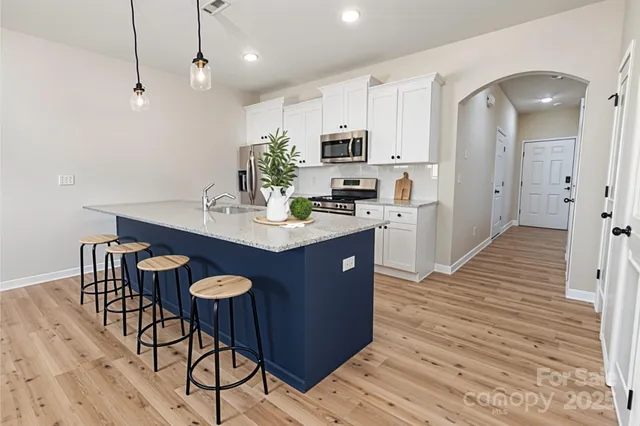 a kitchen with stainless steel appliances granite countertop a sink a stove a dining table and chairs