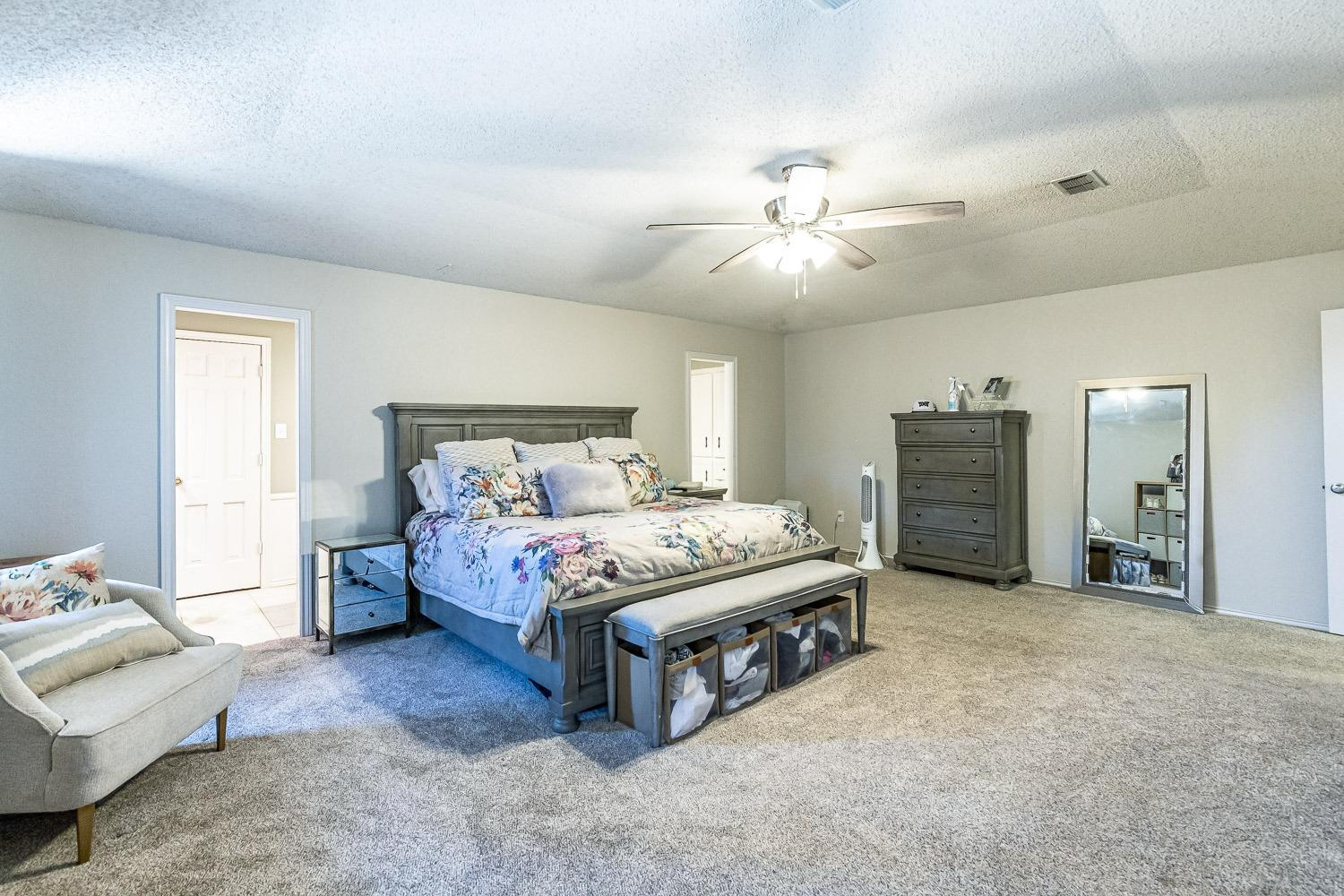 5720 68th Street Lubbock, TX 79424 - Photo 18 of 48 a spacious bedroom with a bed and a chandelier