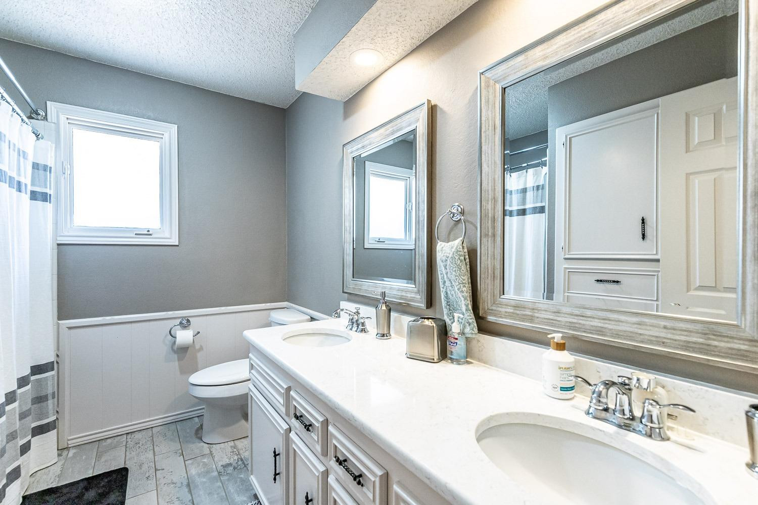 5720 68th Street Lubbock, TX 79424 - Photo 26 of 48 a bathroom with a granite countertop toilet a sink and a mirror