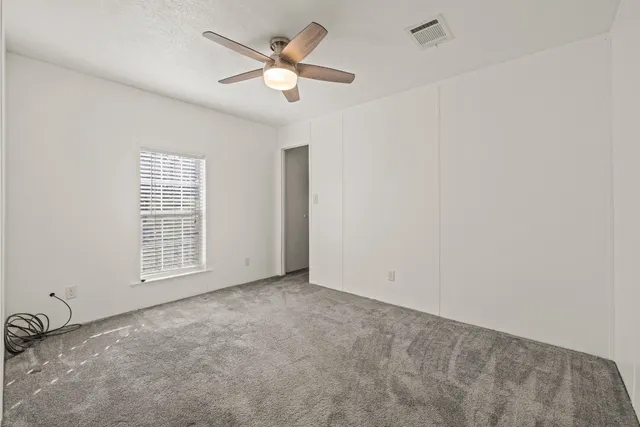 an empty room with windows and fan