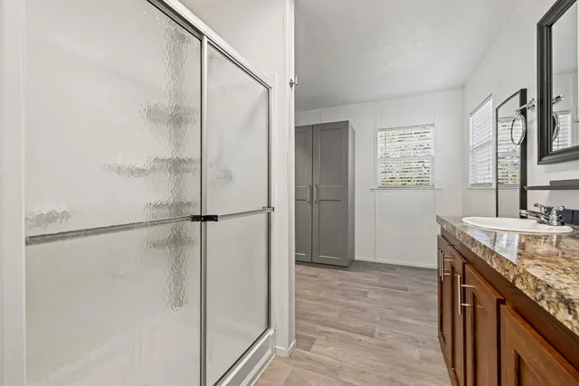 a bathroom with a granite countertop sink a mirror and a shower
