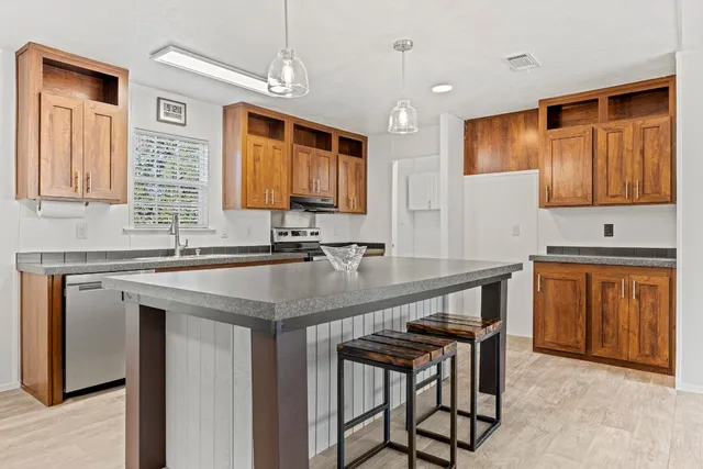 a kitchen with stainless steel appliances granite countertop a sink a stove a counter space and cabinets