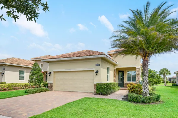 a front view of a house with a garden and palm trees