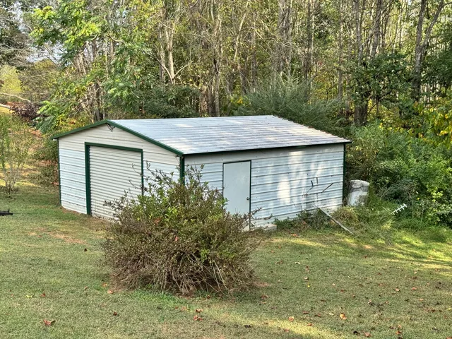 a backyard of a house with plants and large tree