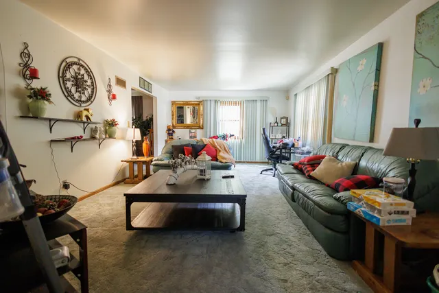 a living room with furniture a clock tv and a window
