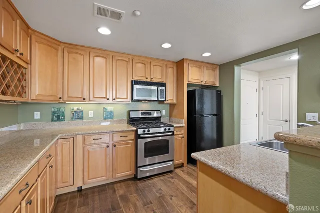 a kitchen with kitchen island granite countertop a stove sink and refrigerator