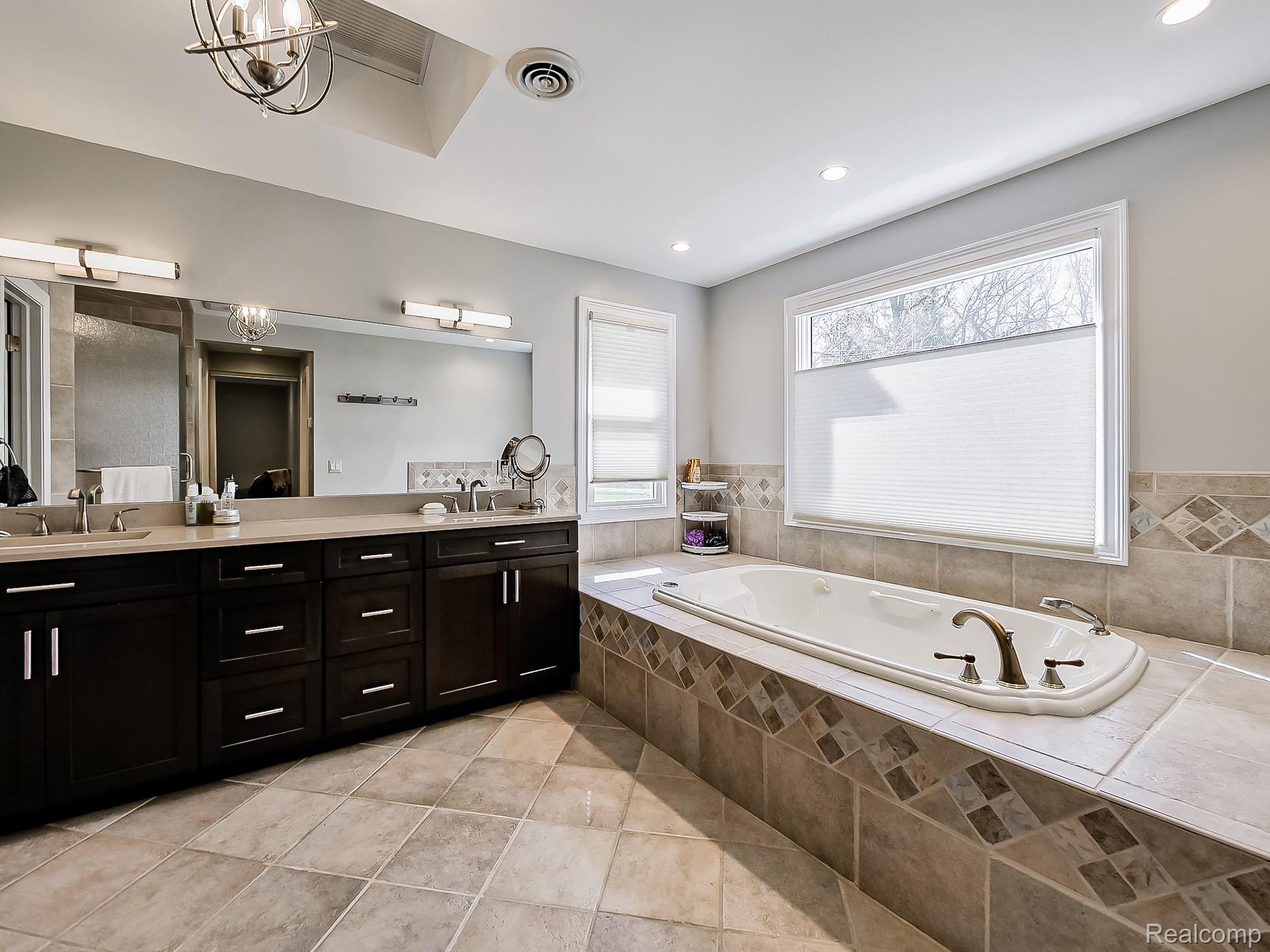 3720 East Clarkston Road Oakland, MI 48363 - Photo 19 of 60 Bathroom with double vanity, a bath, and a chandelier