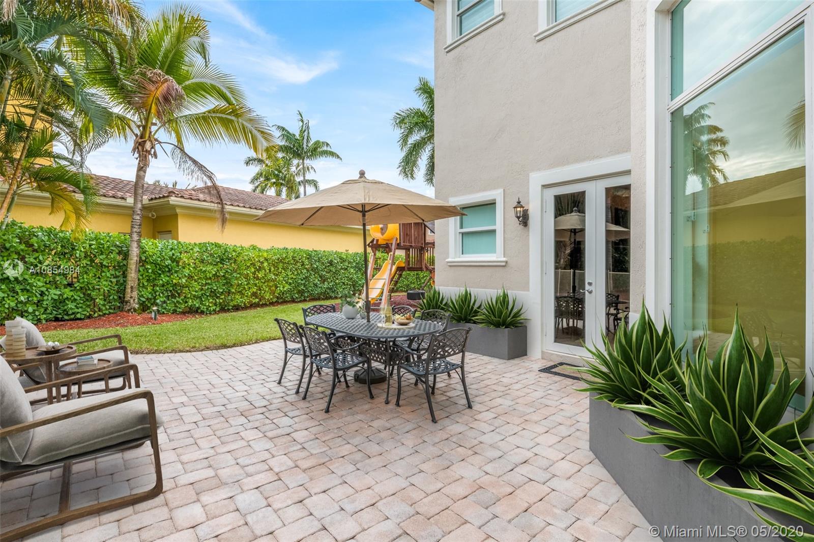 1475 Commodore Way Hollywood, FL 33019 - Photo 35 of 49 a view of a patio with couches table and chairs under an umbrella with palm trees
