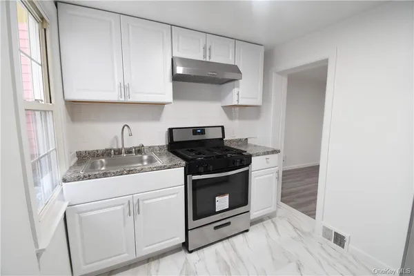 a kitchen with stainless steel appliances granite countertop white cabinets and black stove top oven with granite countertops