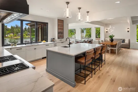 a kitchen with stainless steel appliances a stove a sink a dining table and chairs with wooden floor