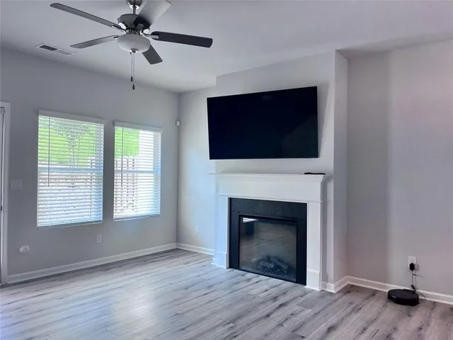 a view of an empty room with wooden floor fireplace and a window
