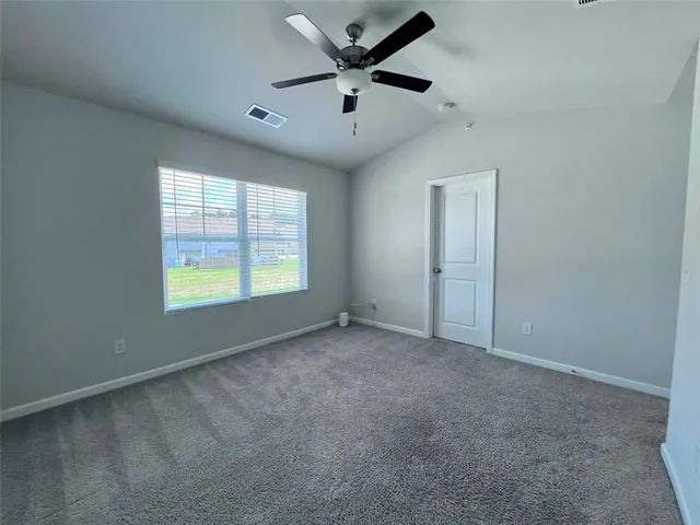 an empty room with ceiling fan and windows