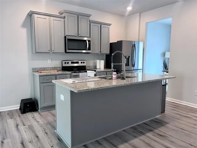 a kitchen with stainless steel appliances granite countertop a stove a sink and a microwave
