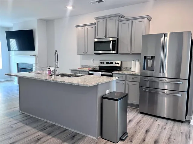 a kitchen with kitchen island granite countertop stainless steel appliances a refrigerator microwave and sink