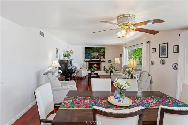 a living room with dining table and paintings on the wall with wooden floor