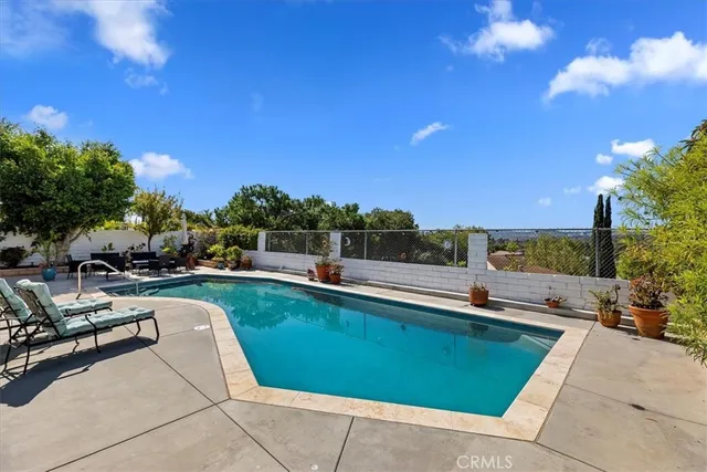 a view of a swimming pool with a lounge chair and couches in the patio