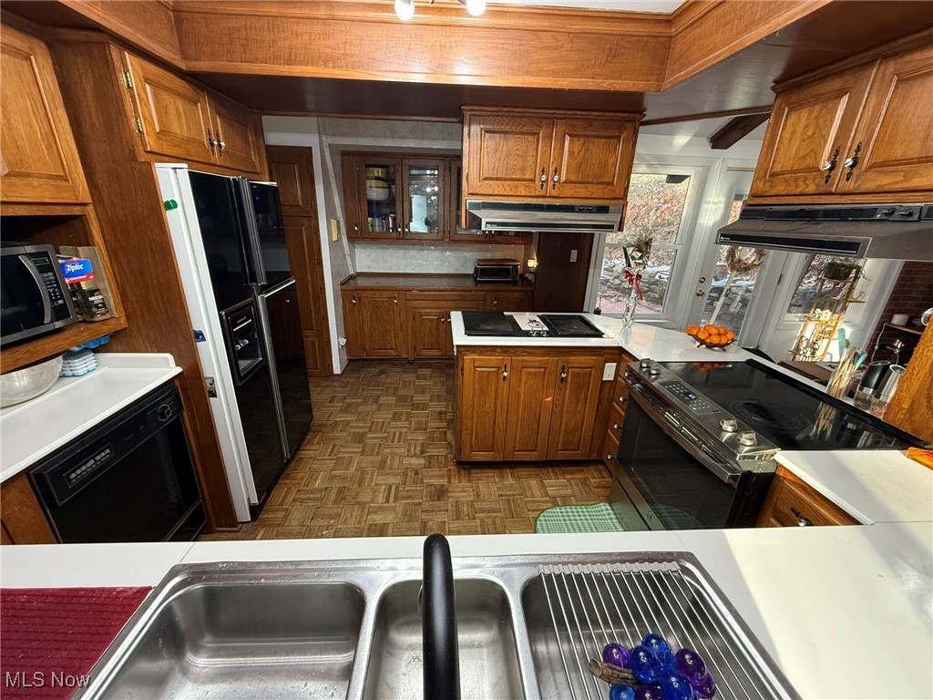 8116 Deer Road Southwest Bowerston, OH 44695 - Photo 18 of 49 Kitchen with black appliances, light countertops, brown cabinets, and under cabinet range hood