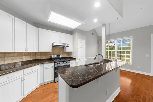 a kitchen with granite countertop a sink a counter top space and cabinets