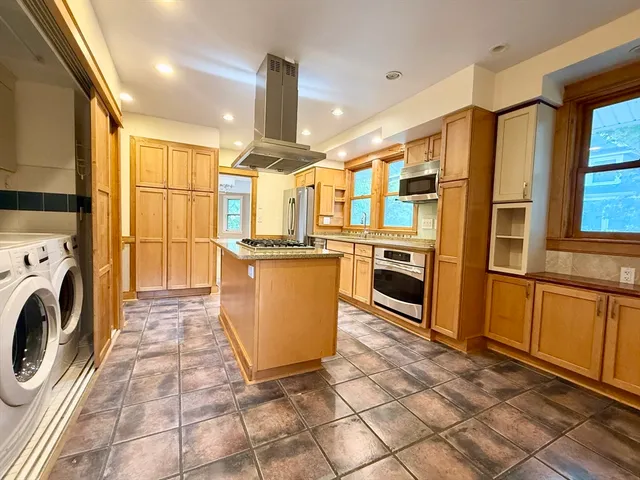 a kitchen with stainless steel appliances granite countertop a refrigerator a oven a stove and a sink with granite countertops