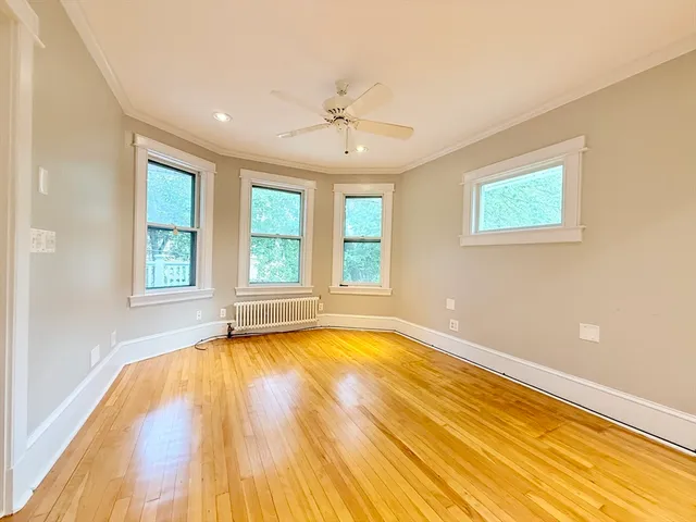 a view of an empty room with window and wooden floor