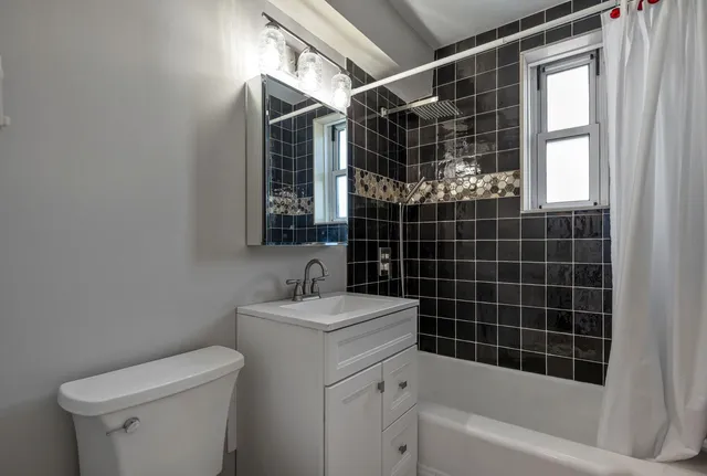 a bathroom with a bathtub shower sink vanity and toilet