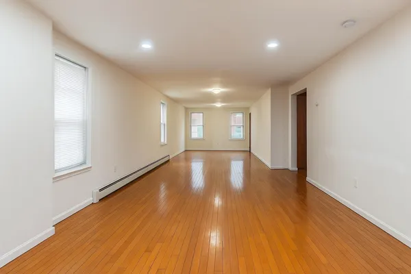 a view of empty room with wooden floor and fan
