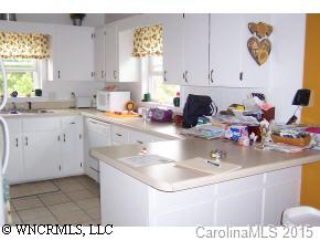 5064 Old Clyde Road Clyde, NC 28721 - Photo 5 of 6 a kitchen with a sink a stove and white cabinets