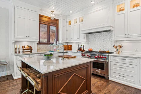 a kitchen with stainless steel appliances granite countertop a stove a refrigerator a dining table and chairs with wooden floor