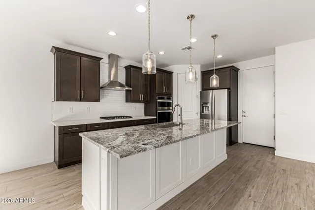a kitchen with stainless steel appliances granite countertop a sink a stove and a wooden floors