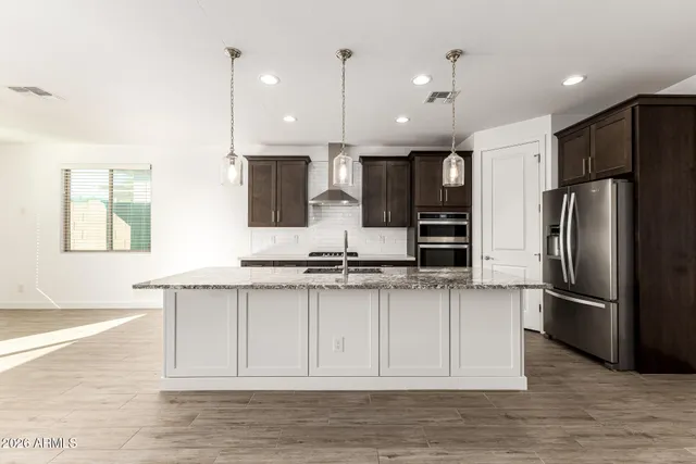 a kitchen with stainless steel appliances granite countertop a refrigerator a sink and a stove