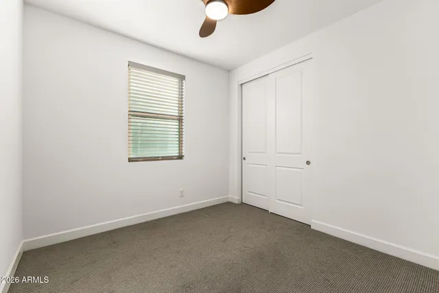 an empty room with ceiling fan and windows