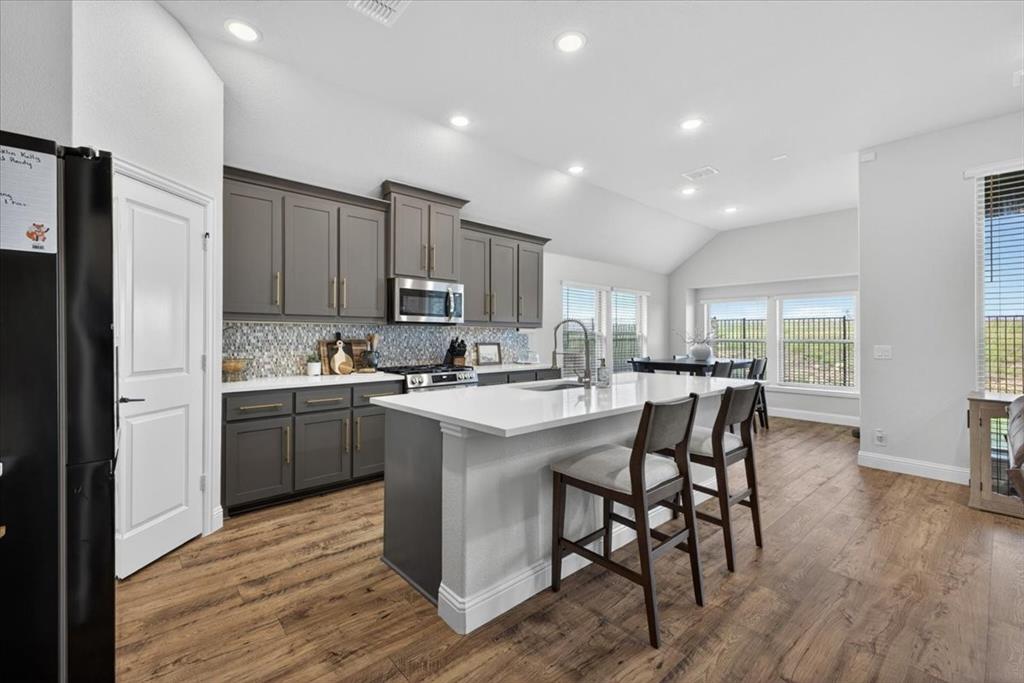 653 Godley Ranch Godley, TX 76044 - Photo 8 of 35 a kitchen with kitchen island granite countertop wooden floors and stainless steel appliances