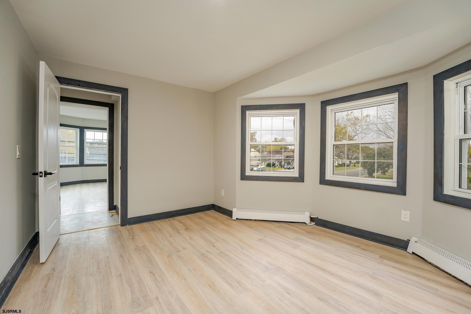 1203 West Mill Road Northfield, NJ 08225 - Photo 22 of 90 an empty room with wooden floor and windows