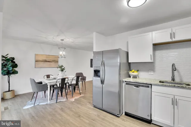 a kitchen with stainless steel appliances granite countertop a refrigerator a stove a sink dishwasher and white cabinets with wooden floor