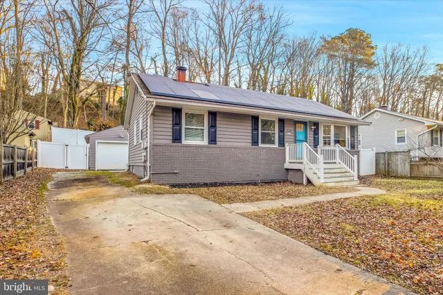 a front view of a house with a dirt yard and a large tree
