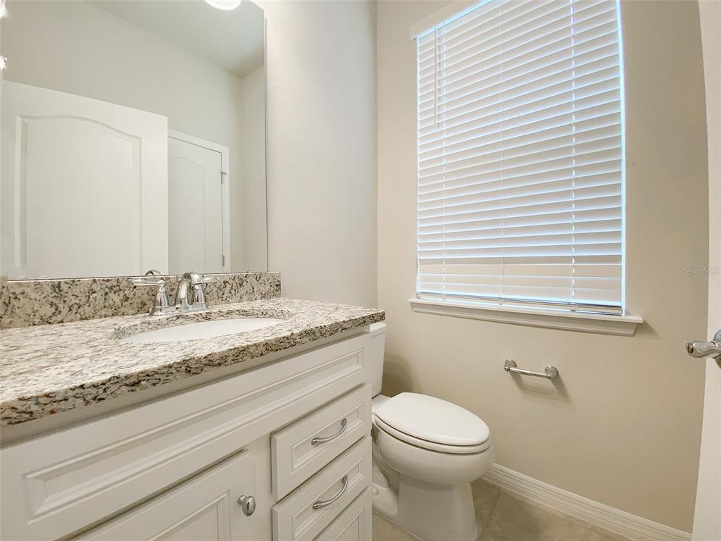 7208 Oakmoss Loop Davenport, FL 33837 - Photo 16 of 46 a bathroom with a granite countertop toilet sink and mirror