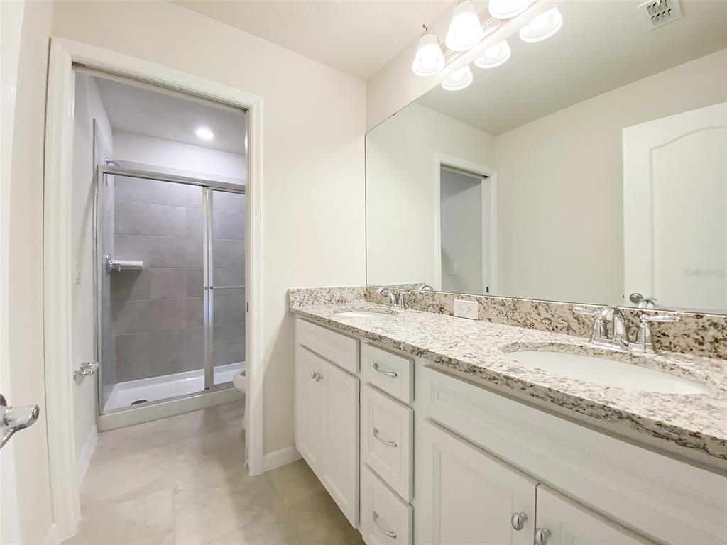 7208 Oakmoss Loop Davenport, FL 33837 - Photo 25 of 46 a bathroom with a granite countertop sink mirror and shower