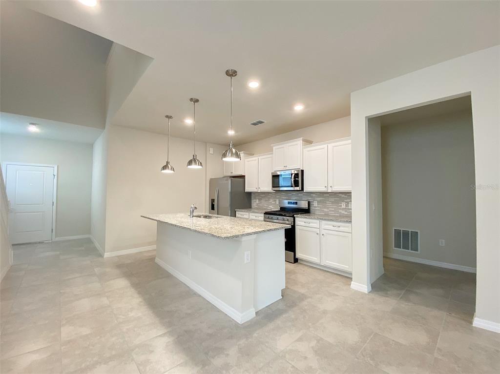 7208 Oakmoss Loop Davenport, FL 33837 - Photo 8 of 46 a large kitchen with kitchen island a sink a stove a refrigerator and a cabinets