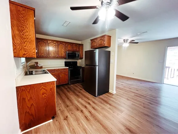 a kitchen with stainless steel appliances granite countertop a refrigerator a sink dishwasher a stove and a dining table with wooden floor