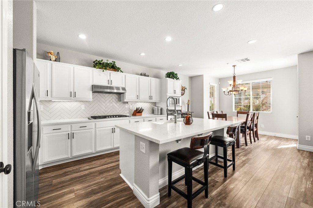 19791 Paso Robles Drive Riverside, CA 92508 - Photo 9 of 29 a kitchen with stainless steel appliances a white table chairs and a refrigerator