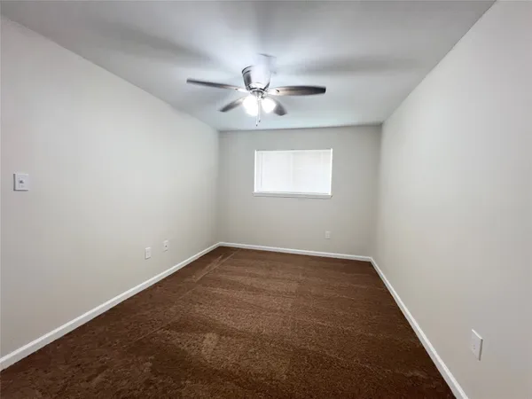 an empty room with a window and ceiling fan