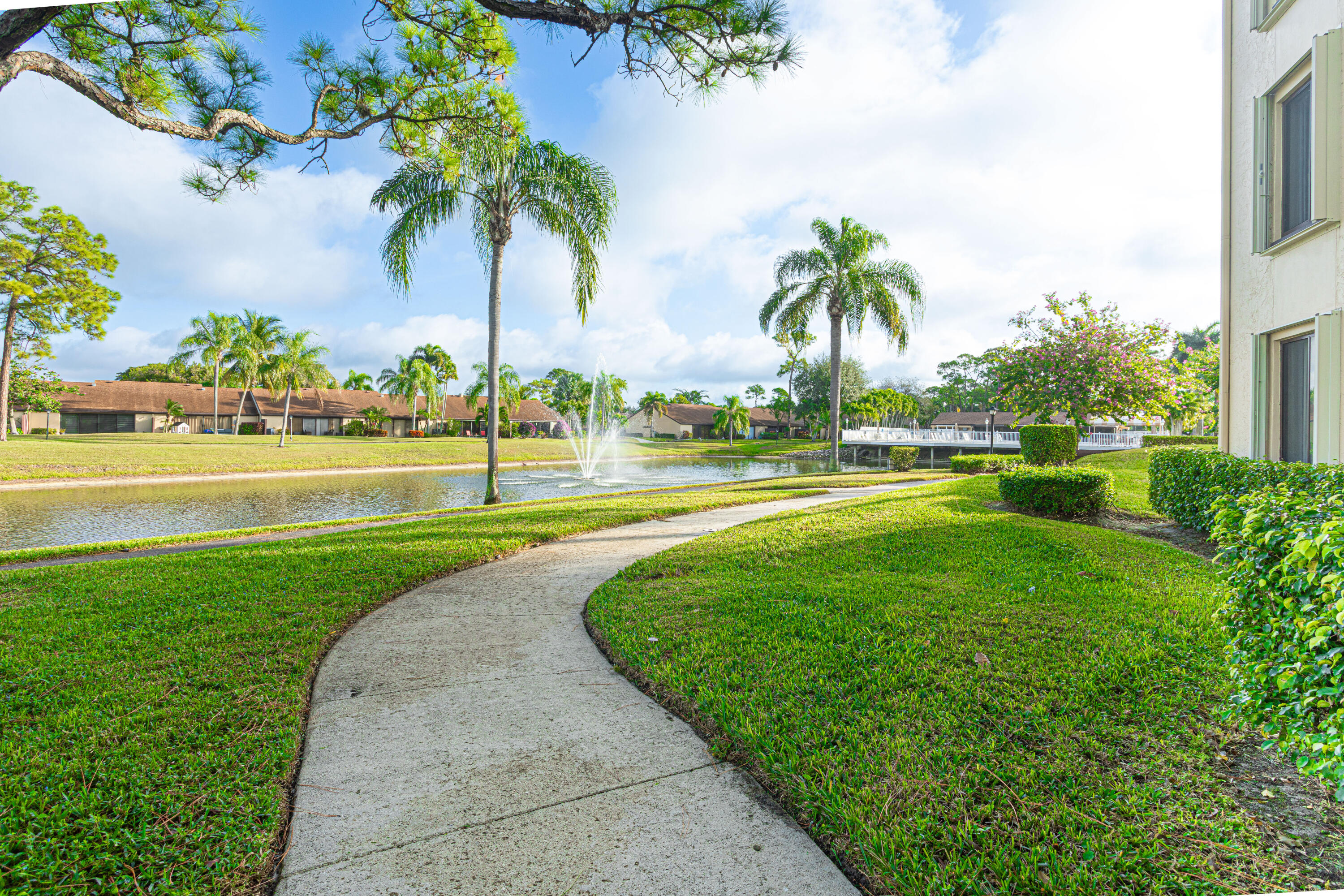 603 Sea Pine Way, Unit C1 Greenacres, FL 33415 - Photo 25 of 32 a view of a swimming pool with a garden and palm trees
