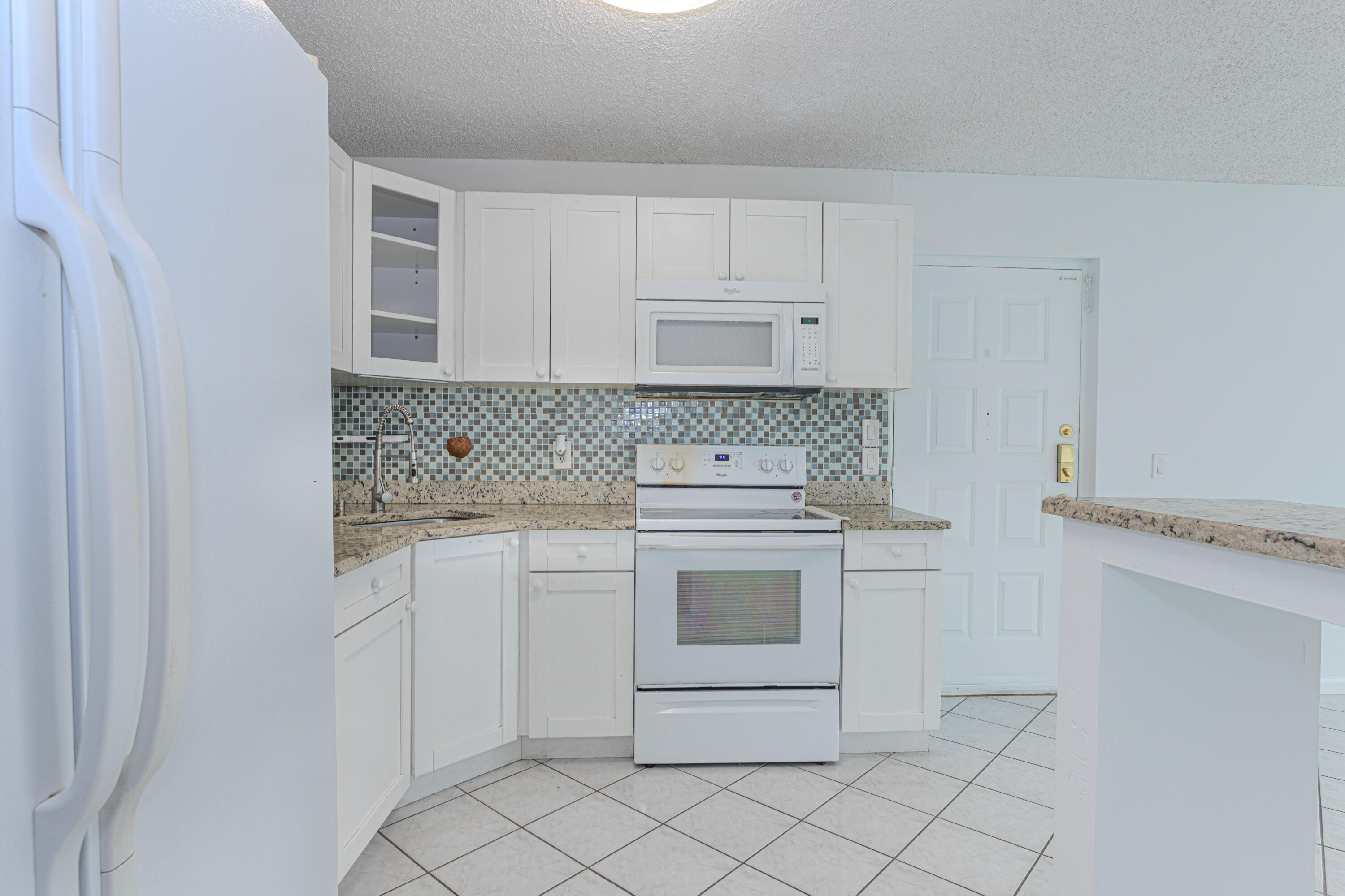 603 Sea Pine Way, Unit C1 Greenacres, FL 33415 - Photo 10 of 32 a kitchen with white cabinets and white appliances